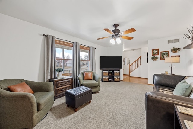 living room featuring visible vents, carpet flooring, ceiling fan, and stairway