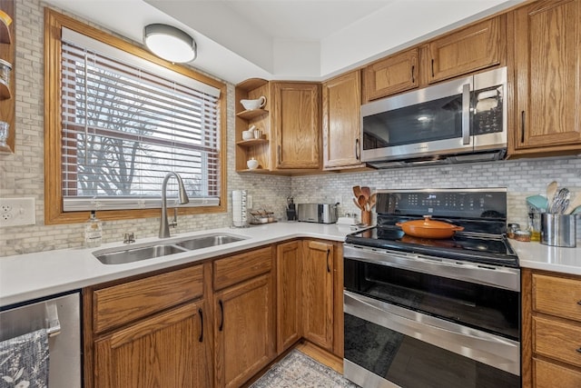 kitchen with backsplash, stainless steel appliances, a sink, and light countertops