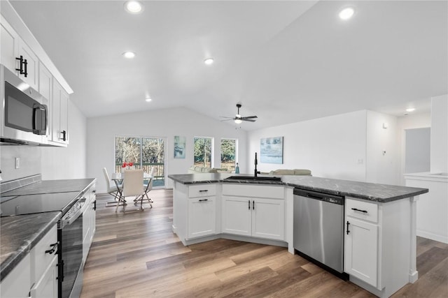 kitchen featuring stainless steel appliances, lofted ceiling, light wood-style floors, white cabinetry, and a sink