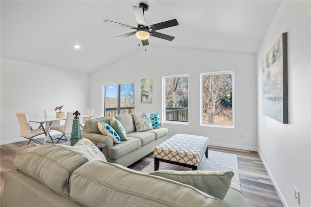 living room featuring ceiling fan, vaulted ceiling, baseboards, and wood finished floors