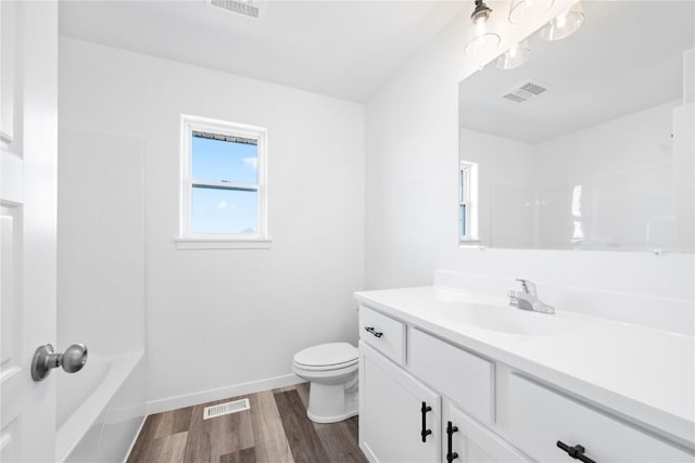 bathroom featuring toilet, vanity, wood finished floors, and visible vents