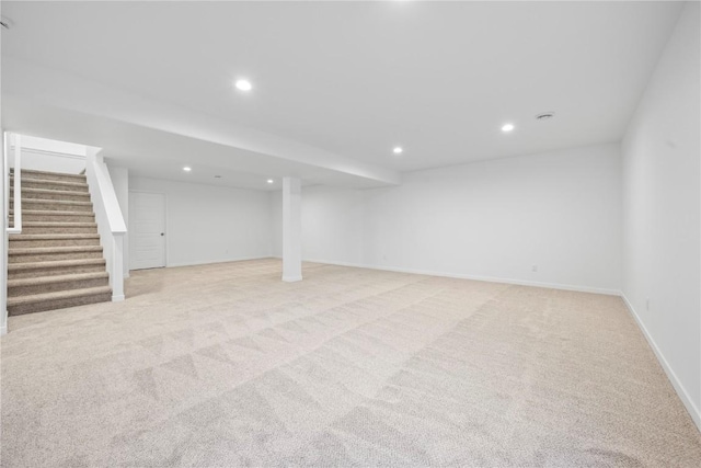 finished basement featuring light carpet, stairs, baseboards, and recessed lighting