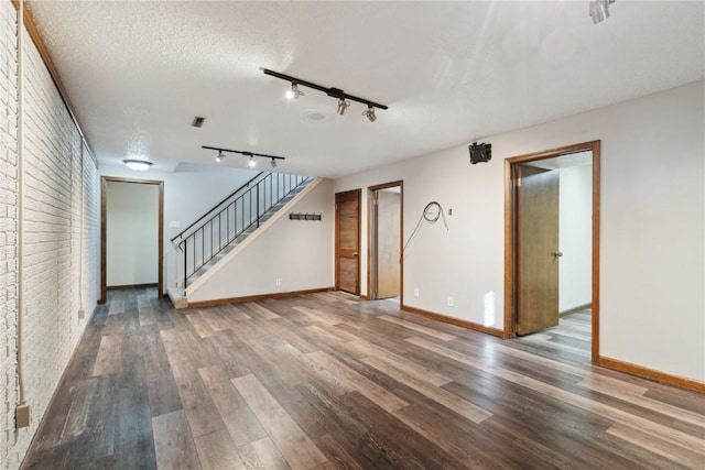 unfurnished living room featuring wood finished floors, a textured ceiling, baseboards, and stairs