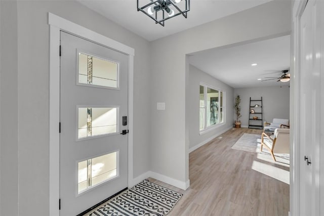 foyer featuring light wood-type flooring, a ceiling fan, and baseboards