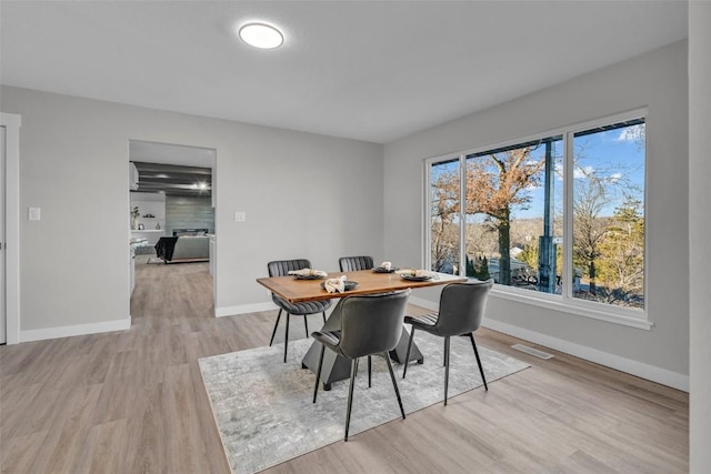 dining area featuring baseboards, visible vents, and light wood finished floors