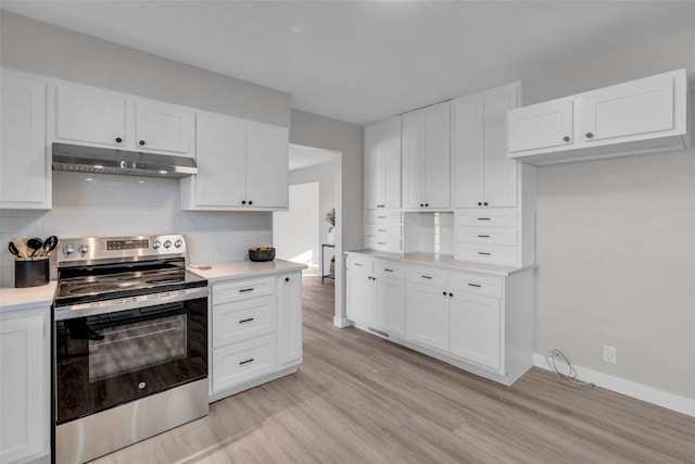 kitchen featuring tasteful backsplash, light countertops, white cabinetry, under cabinet range hood, and stainless steel electric range