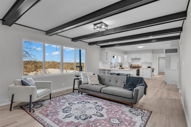 living room featuring light wood finished floors, beamed ceiling, and baseboards