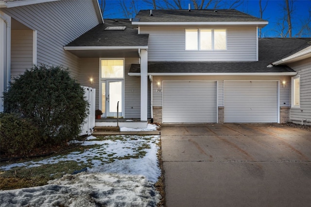 view of front facade featuring concrete driveway, roof with shingles, and an attached garage