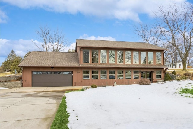 view of front facade with concrete driveway, an attached garage, brick siding, and a shingled roof