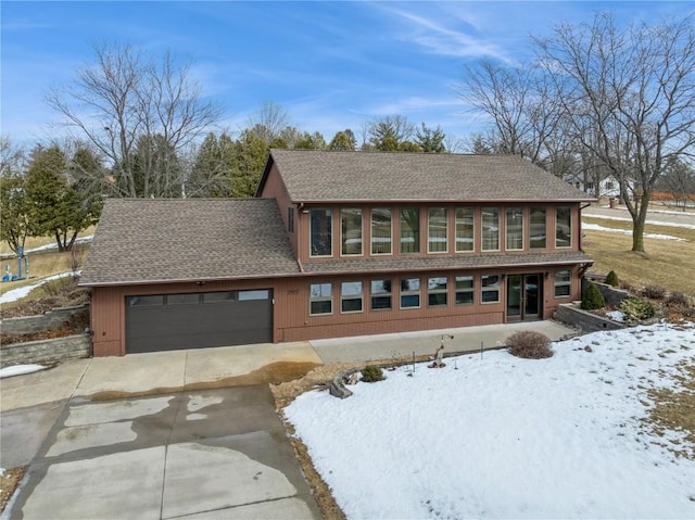 view of front of home featuring concrete driveway, a garage, and a shingled roof