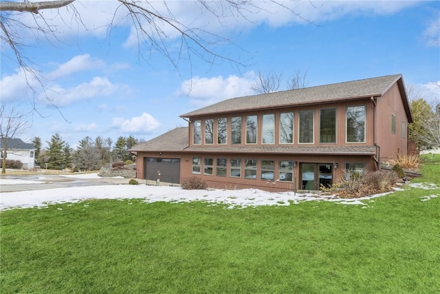 rear view of property with a lawn and an attached garage