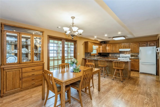 dining space with light wood-style flooring, french doors, and an inviting chandelier