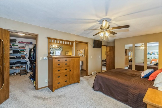 bedroom featuring visible vents, baseboards, a closet, a walk in closet, and light colored carpet