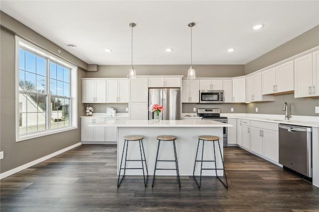 kitchen featuring a kitchen island, white cabinetry, baseboards, appliances with stainless steel finishes, and dark wood-style floors