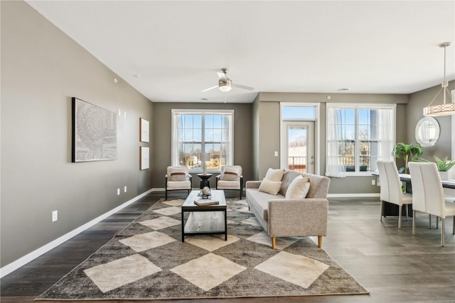 living room with a ceiling fan, baseboards, and wood finished floors