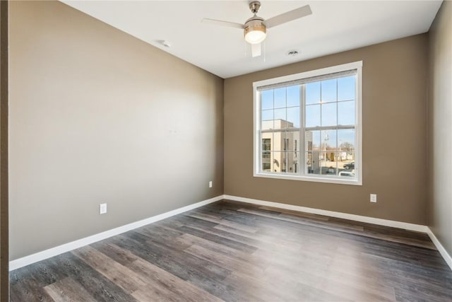 spare room with dark wood-style floors, baseboards, and a ceiling fan