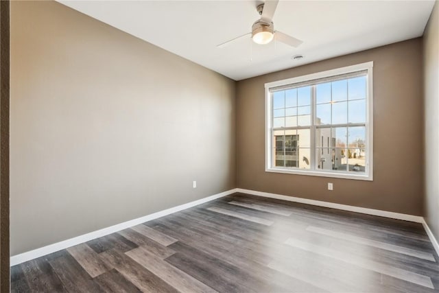 unfurnished room featuring dark wood-style flooring, ceiling fan, and baseboards