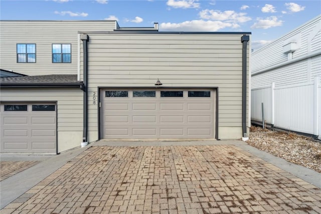 garage with decorative driveway and fence