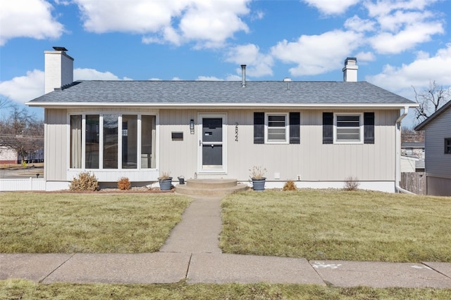 view of front of home featuring roof with shingles, a chimney, and a front yard