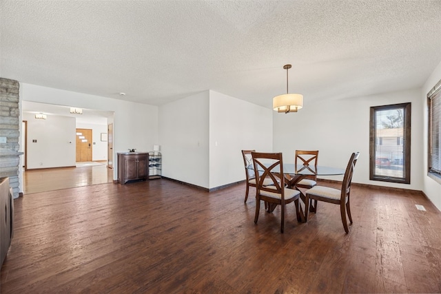 dining room with a textured ceiling, baseboards, and dark wood-type flooring