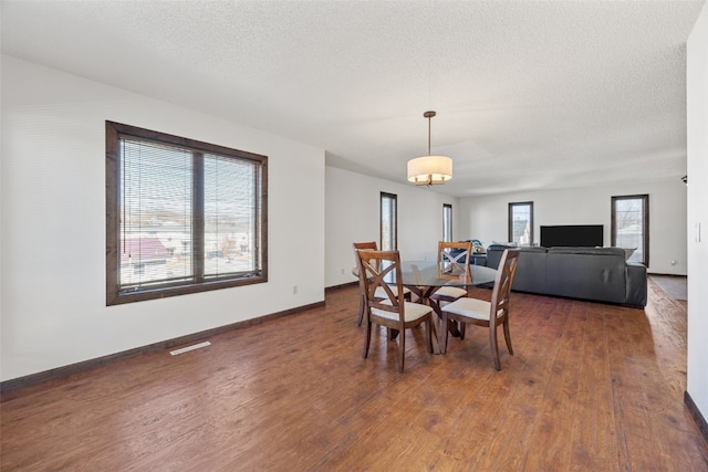 dining area featuring a textured ceiling, baseboards, and wood finished floors