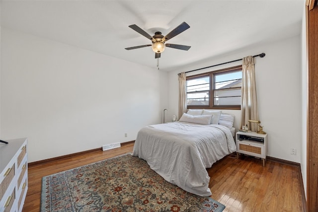 bedroom featuring baseboards, visible vents, ceiling fan, and wood finished floors