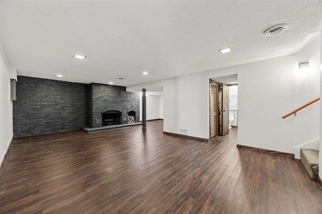 unfurnished living room with stairs, a brick fireplace, wood finished floors, and visible vents