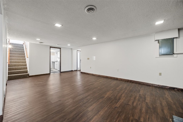 empty room with stairway, dark wood finished floors, visible vents, and baseboards