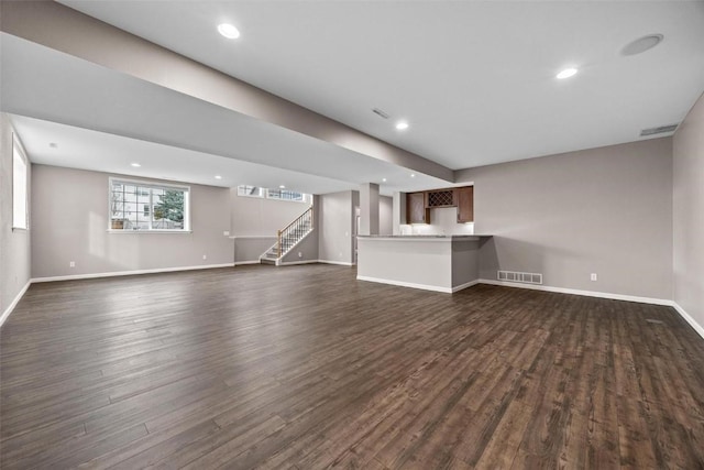 unfurnished living room featuring stairway, baseboards, visible vents, and dark wood-style flooring