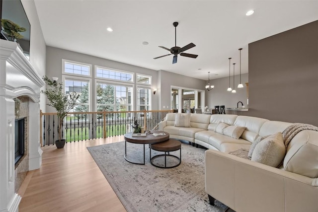 living room with a high end fireplace, a wealth of natural light, light wood-style flooring, and recessed lighting