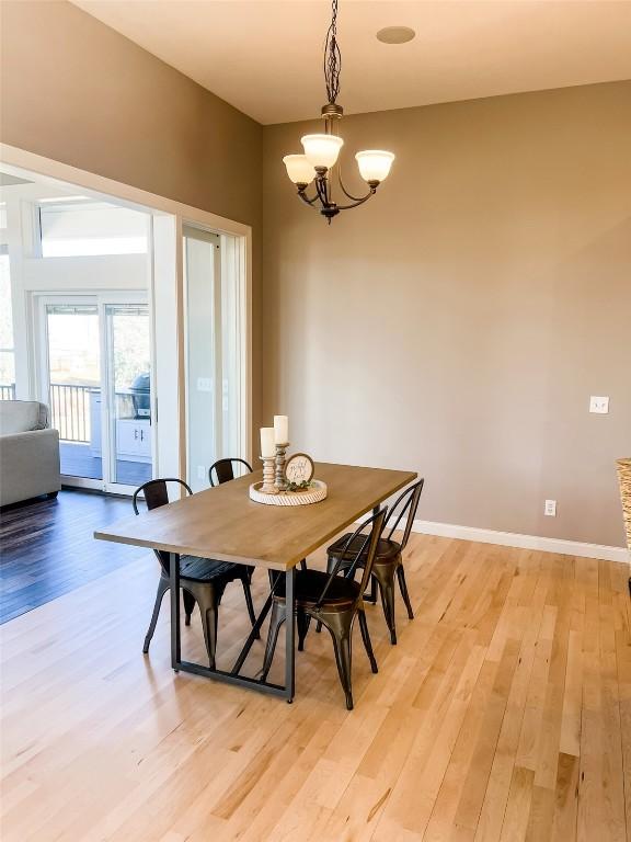 dining area featuring light wood-style floors, a chandelier, and baseboards