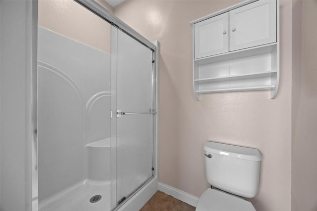 full bath with a stall shower, toilet, and baseboards