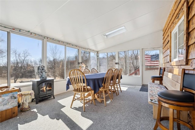 sunroom / solarium featuring a wood stove, plenty of natural light, and vaulted ceiling