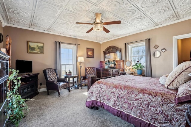 bedroom with an ornate ceiling, carpet, crown molding, a ceiling fan, and baseboards