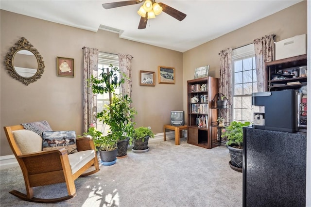 living area with carpet floors, a ceiling fan, and baseboards