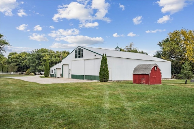 view of barn with fence and a yard