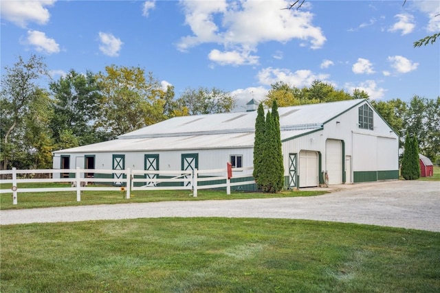 exterior space featuring a detached garage, metal roof, an outbuilding, fence, and a front lawn