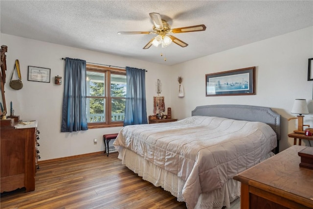 bedroom with ceiling fan, a textured ceiling, baseboards, and wood finished floors