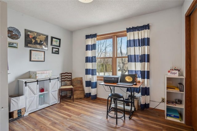 office with a textured ceiling, baseboards, and wood finished floors