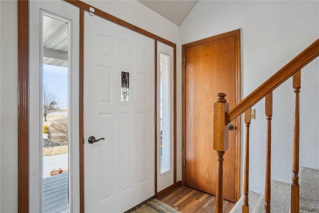 foyer entrance featuring stairs, vaulted ceiling, and wood finished floors