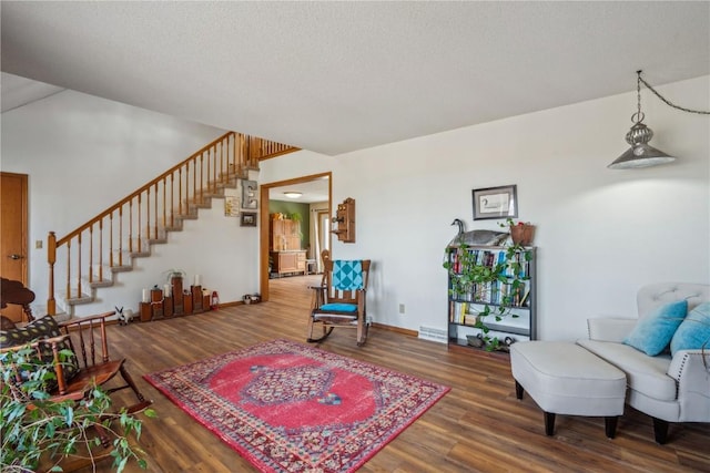 sitting room featuring baseboards, a textured ceiling, stairway, and wood finished floors