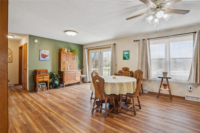 dining area featuring light wood-type flooring, visible vents, and a textured ceiling