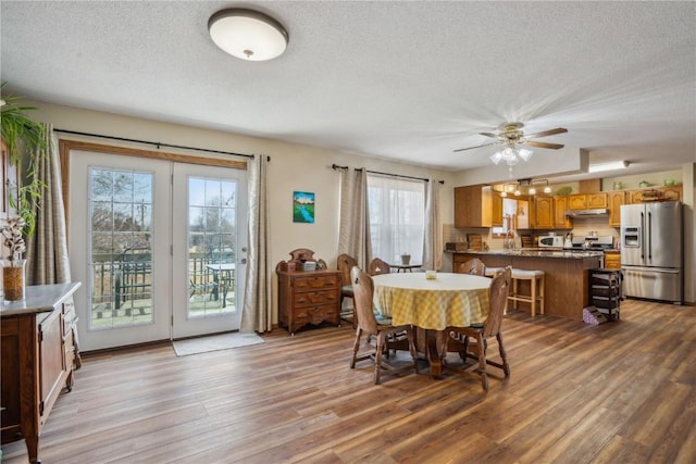 dining space with ceiling fan, a textured ceiling, and wood finished floors