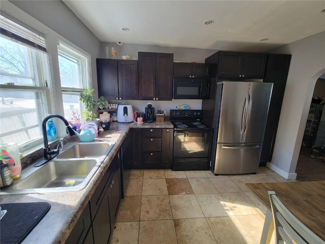 kitchen featuring black appliances, arched walkways, light countertops, and a sink