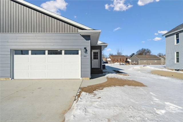 view of snow covered exterior with a garage and board and batten siding