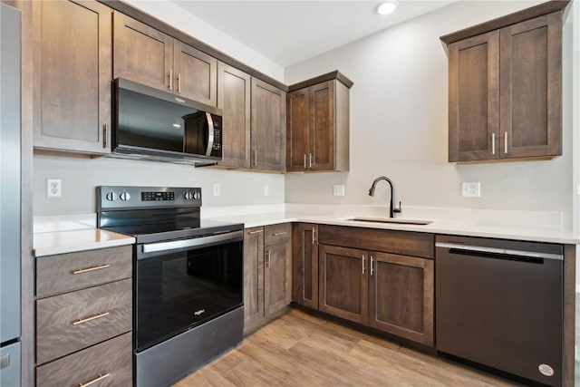 kitchen with stainless steel appliances, light wood-style floors, light countertops, and a sink