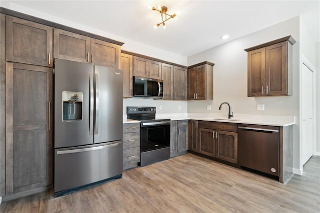 kitchen with baseboards, stainless steel appliances, light countertops, light wood-style floors, and a sink