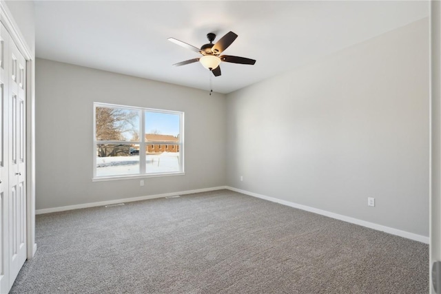 unfurnished bedroom featuring a closet, carpet, a ceiling fan, and baseboards