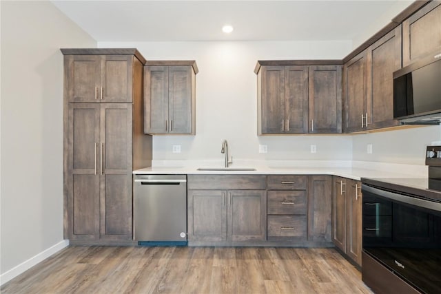 kitchen featuring appliances with stainless steel finishes, light wood-type flooring, light countertops, and a sink