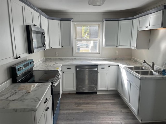 kitchen featuring appliances with stainless steel finishes, a sink, light stone counters, and dark wood-style floors